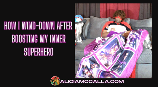 Alicia McCalla sitting on the couch writing in her journal and covered in the I am a superhero Blanket