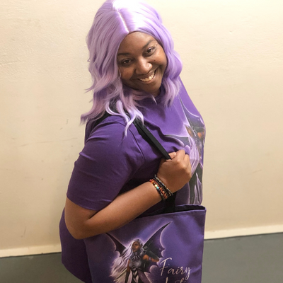 Alicia McCalla Carrying Dark Fairy Justice Tote Bag and Wearing a T-Shirt with Lavendar Wig